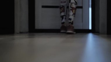 Renkli taytlı kız spor ayakkabılarını giyer ve evden çıkar.