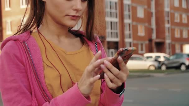 Selfie sportivo. Giovane e bella ragazza in abbigliamento sportivo guardando il telefono e sorridendo mentre prende selfie al telefono con la luce del sole serale su sfondo — Video Stock