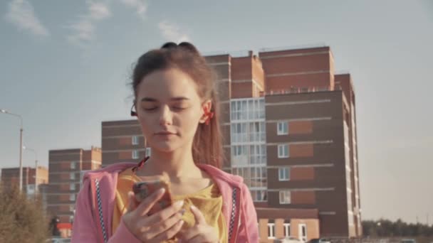 Selfie desportiva. Menina jovem e bonita em roupas esportivas olhando para o telefone e sorrindo enquanto toma selfie no telefone com luz solar à noite no fundo — Vídeo de Stock