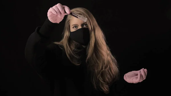 Дівчинка в чорній масці тримає пробірку з кров'ю і написом covid-19. Розташований на чорному тлі. Медична концепція та медична концепція. Епідемія коронавірусу — стокове фото