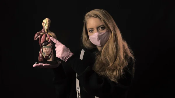 Дівчина в рожевій масці і стрічці з написом ковадла 19 вказує на легені на анатомічну модель людини. Охорона здоров'я та медична концепція. 4k. епідемія коронавірусу — стокове фото