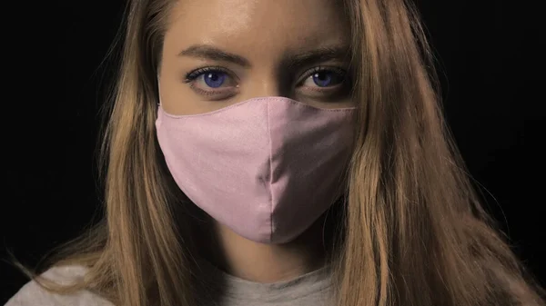 Дівчина в рожевій масці і блакитні очі тримають стрічку з написом covid-19. Медична концепція та медична концепція. Закройте портрет. Коронавірус Епідемія, хвороба, пандемія — стокове фото