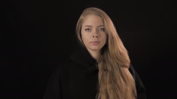 Egy fiatal nő fekete pulóverben, arany hajjal a kamerába néz. Közelről. 4k — Stock videók
