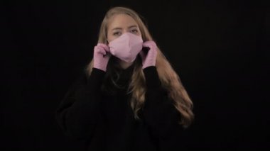 Pembe maskeli kız maskesini çıkarıp öksürüyor. Siyah arka planda izole edilmiş. Sağlık ve tıbbi konsept. Portreyi kapat. 4 bin. Coronavirus Salgını, Hastalık, Salgın