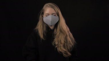 Genç kadın arka arkaya bir sürü maske takıyor. Siyah arka planda izole edilmiş. Sağlık ve tıbbi konsept. Portreyi kapat. 4 bin. Coronavirus Salgını, Hastalık, Salgın
