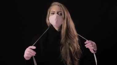Pembe maskeli kız üzerinde covid-19 yazan bir kaset tutuyor. Siyah arka planda izole edilmiş. Sağlık ve tıbbi konsept. Portreyi kapat. 4 bin. Coronavirus Salgını, Hastalık, Salgın