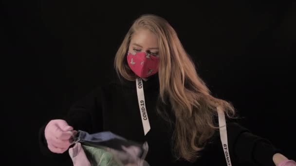 Flicka med vit tejp och inskriptionen covid 19 håller många andra masker och twist. Isolerad på svart bakgrund. Sjukvård och medicinskt koncept. Epidemi med coronavirus — Stockvideo