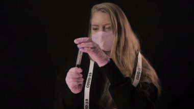 Kız elinde bir test tüpünü kanla açıyor ve yazıtlar 19 'u gösteriyor ve içiyor. Siyah arka planda izole edilmiş. Sağlık ve tıbbi konsept. Portreyi kapat. 4 bin. Koronavirüs salgını