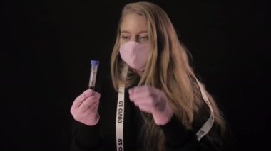 Kız elinde bir test tüpünü kanla açıyor ve yazıtlar 19 'u gösteriyor ve içiyor. Siyah arka planda izole edilmiş. Sağlık ve tıbbi konsept. Portreyi kapat. 4 bin. Koronavirüs salgını