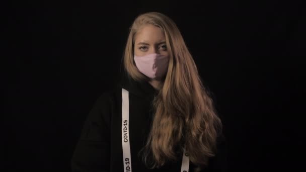 Flicka i rosa mask och ett band med inskriptionen covid 19 poäng till klockan tiden håller på att rinna ut. Sjukvård och medicinskt koncept. 4k. Epidemi med coronavirus — Stockvideo