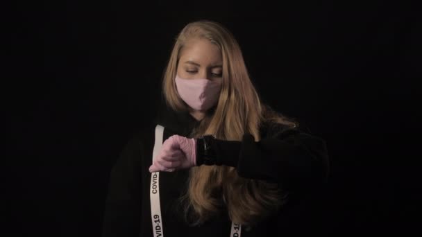 Flicka i rosa mask och ett band med inskriptionen covid 19 poäng till klockan tiden håller på att rinna ut. Sjukvård och medicinskt koncept. 4k. Epidemi med coronavirus — Stockvideo