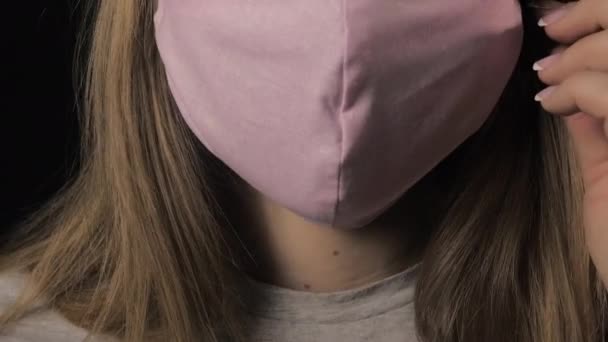Дівчина прибирає рожеву маску і починає кашляти. Ізольовані на чорному тлі. Охорона здоров'я та медична концепція. Портрет крупним планом. 4k. епідемія коронавірусу — стокове відео