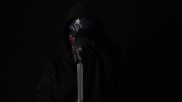 무시무시 한 마스크를 쓴 사람 이 비문이 붙어 있는 흰색 테이프를 손에 들고 있다. 검은 배경에 고립되어 있습니다. 건강 관리와 의학 개념. 코로나 바이러스 유행성, 질병, 유행병. 미국의 마스크 — 비디오