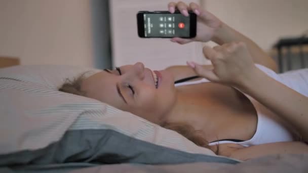 Sexy dziewczyna w a biały czołg top i niebieski krótki dżinsowe szorty mówi na telefon i śmieje się — Wideo stockowe