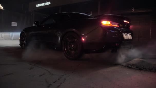 TOMSK, RUSSIA - March 30, 2020: Chevrolet Camaro ZL1 the Exorcist burns rubber at night near buildings back view — Stock Video