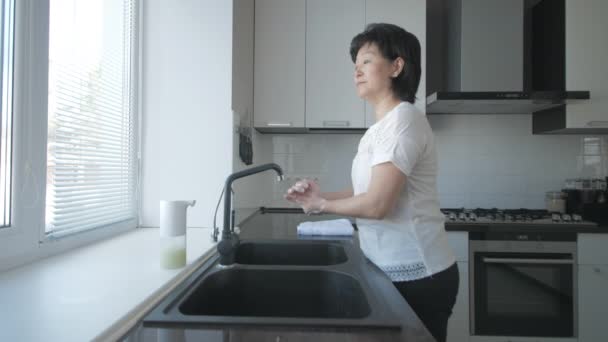 Aziatische vrouw wast handen met zeep in de keuken — Stockvideo