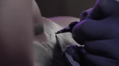 Mavi eldivenli dövme ustası bir dövme yapıyor, makro çekim, yavaş çekim.