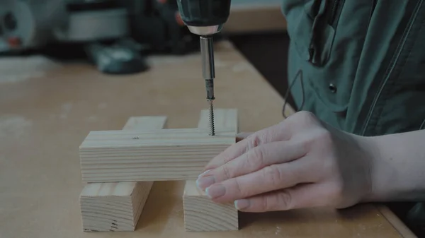 Ragazza con manicure torce un cacciavite in un bianco di legno — Foto Stock