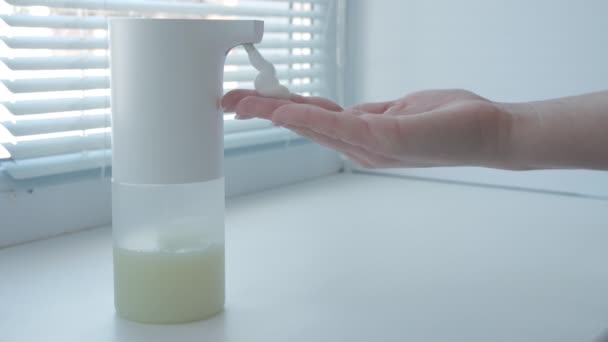 Otomatik köpük sabun makinesi kullanan, ellerini yıkayan, pencerenin kenarında, makrosu olan bir kız. — Stok video