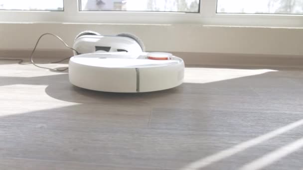 Witte robot stofzuiger op linoleum houten vloer slimme reinigingstechnologie — Stockvideo