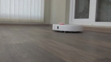 Linolyum ahşap zemin üzerinde beyaz robotik süpürge akıllı temizlik teknolojisi