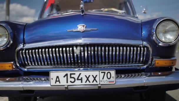 TOMSK, RUSIA - 21 de junio de 2019: El coche retro azul Volga gas-21 en la calle en un clima soleado. Vista frontal, exterior. mariposa voladora en cámara lenta — Vídeo de stock