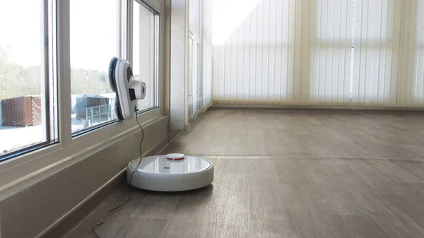 Beyaz robotik süpürge ve robot pencere temizleyicisi birlikte çalışır. Akıllı temizlik teknolojisi