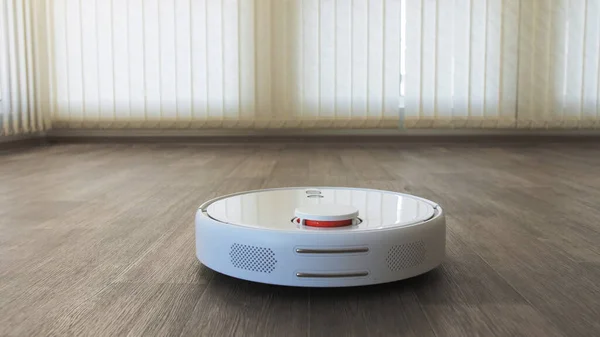 Linolyum ahşap zemin üzerinde beyaz robotik süpürge akıllı temizlik teknolojisi