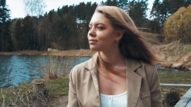 Güzel sarışın kadın gölün yakınındaki bir parkta oturup dinleniyor. Yan görünüm