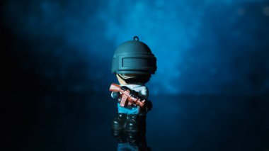 TOMSK, RUSSIA - 21 Mayıs 2020: Pompalı tüfekli küçük adam renk arkaplanına karşı bir masada duruyor