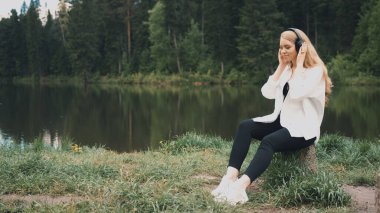 TOMSK, RUSSA - 23 Mayıs 2020: Siyah sony WH 1000xm3 kulaklıkla müzik dinleyen doğal görünümlü güzel sarışın kadın