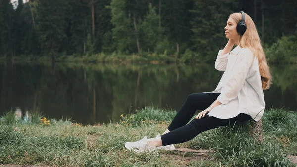 TOMSK, RUSSA - 23 Mayıs 2020: Siyah sony WH 1000xm3 kulaklıkla müzik dinleyen doğal görünümlü güzel sarışın kadın