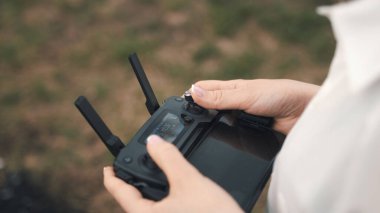 Dişi eller, uzaktan kumandayı tutuyor.