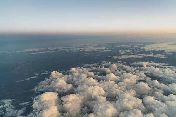 View from an airplane flying above clouds, at dawn in the morning