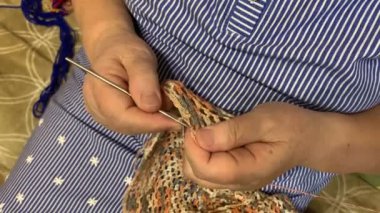 Güzel bir pelerin ören yaşlı bir kadının ellerinin yakın çekimi. Tığ işi. İğne işi.