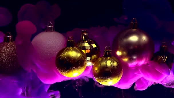 Gouden Glimmende Kerstballen Violette Inkt Water Een Zwarte Achtergrond Winter — Stockvideo