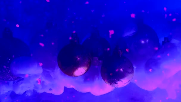 青い雪の背景に美しいクリスマスボール 水にピンクと青のインク 冬の背景 クリスマスの背景概念 宇宙素晴らしい背景 — ストック動画