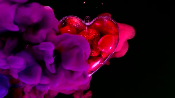 神奇的玻璃心脏里面的红色心脏在一个彩色的空间背景 情人节的概念二月十四日 黑色底色上的红色 蓝色和紫色墨水 — 图库视频影像