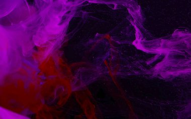 Pink watercolor ink in water on a black background. Colored spac