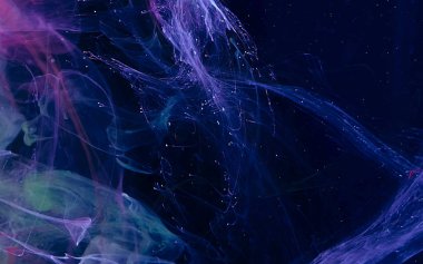 Colored watercolor ink in water on a black background.