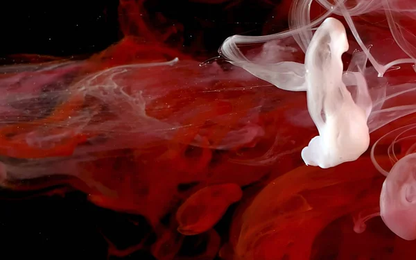 Red and white watercolor ink in water on a black background. — Stockfoto