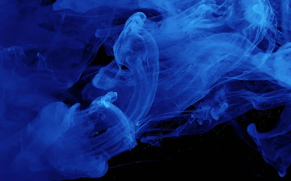 Blue watercolor ink in water on a black background. Colored space background. Abstract background. Stylish trending screensaver.