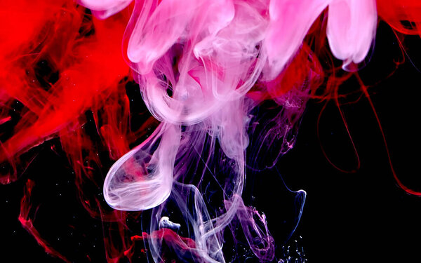 Red and white watercolor ink in water on a black background. Cosmic magic background. Abstract background. Cool trending screensaver.