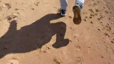 PETERSBURG, RUSSIA - 13 Mayıs 2020: bir adam gri pantolon ve gri spor ayakkabılar ile plaj boyunca koşuyor. Sabah koşusu. Spor yaz konsepti.