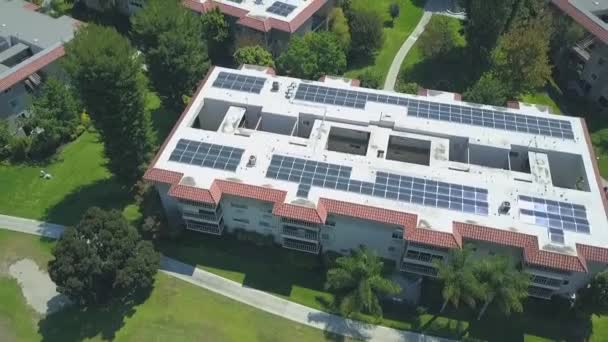 Luchtfoto stijgende zicht boven zonnig dak appartement ontwikkeling complex met zonnepanelen genereren van schone energie — Stockvideo