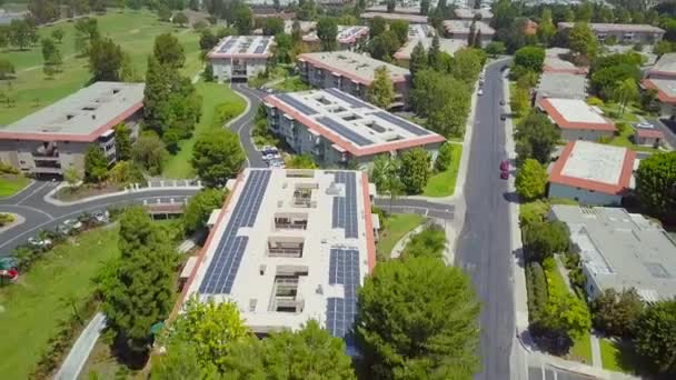 Vista trasera aérea soleada por encima de la jubilación paneles solares de techo complejo condominio que generan electricidad solar — Vídeo de stock