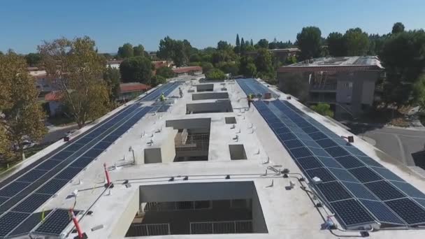 Arbeiter, die Sonnenkollektoren auf dem Dach eines Gebäudekomplexes installieren, werden aus der Luft überrollt — Stockvideo