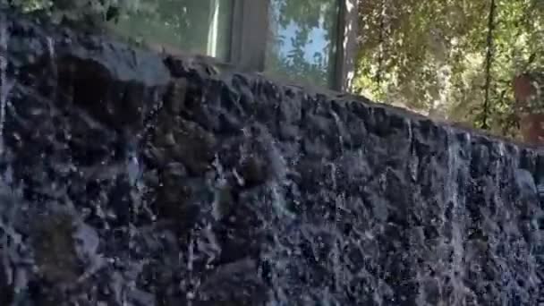 Cascata de jardim espumante que flui sobre a parede de rocha pequena na frente do jardim da janela da casa, espumante, cachoeira — Vídeo de Stock
