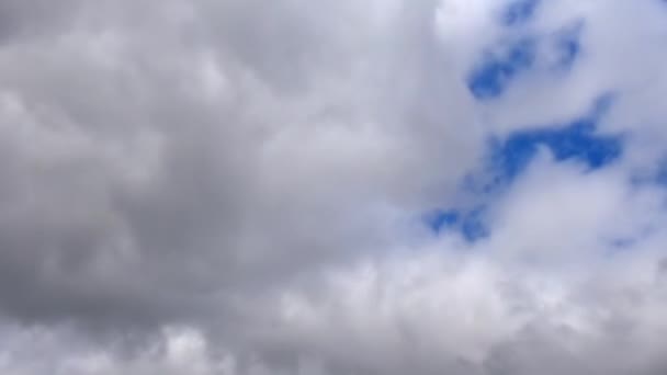Проміжок часу сірих і білих темних дощових хмар, що рухаються крізь небо з плямою синього — стокове відео
