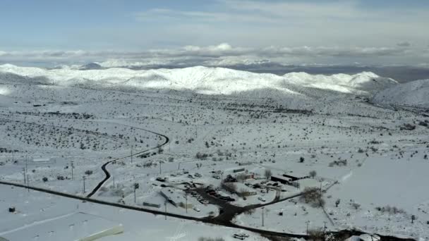 Vista aérea sobre la comunidad de la ciudad cubierta de nieve blanca, montaña en distante — Vídeos de Stock